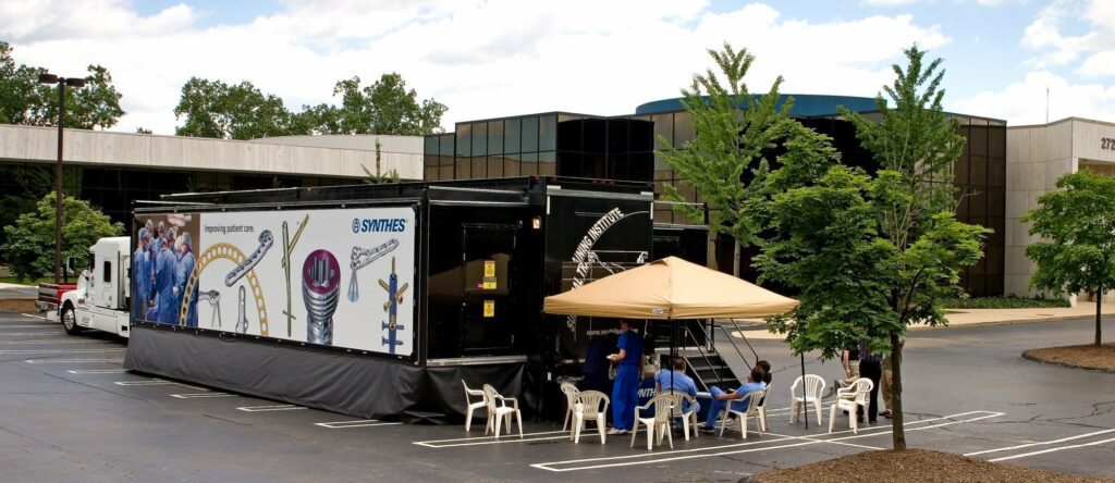 medical trailer that is black, with a yellow tent and some chairs infront of it