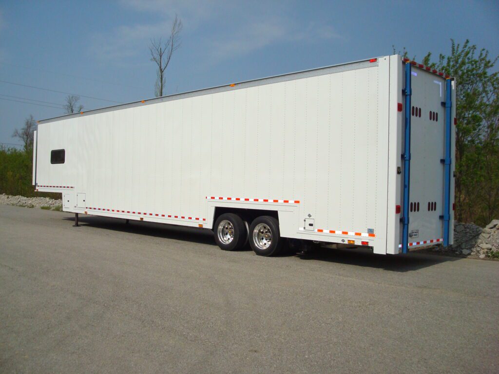 A white semi-trailer is parked on an asphalt surface under a clear sky.