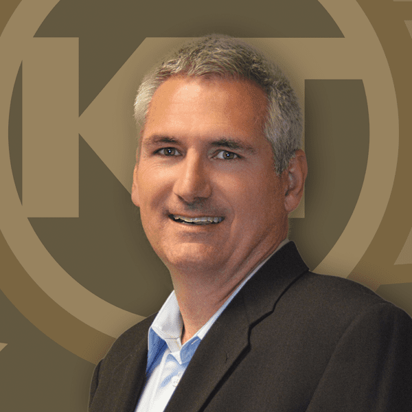 A smiling individual is posing for a portrait against an emblematic background.